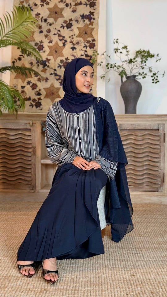 Woman in a blue and gray outfit sitting in a room with decorative elements.